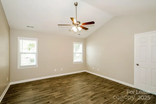 a view of an empty room with window and wooden floor