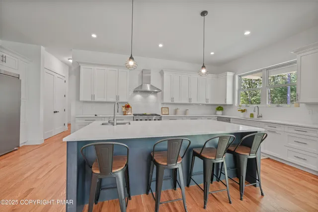 a kitchen with stainless steel appliances kitchen island granite countertop a dining table chairs and white cabinets