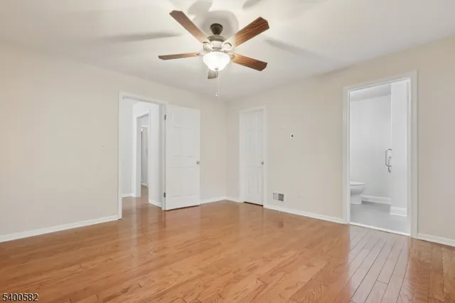 an empty room with wooden floor and ceiling fan