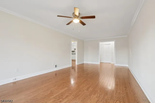 an empty room with wooden floor ceiling fan and windows