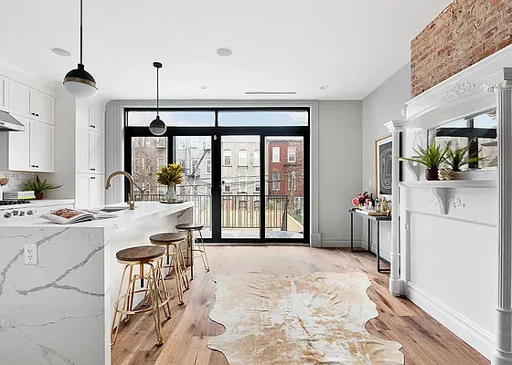 a view of a kitchen with kitchen island a large window cabinets a sink and stainless steel appliances