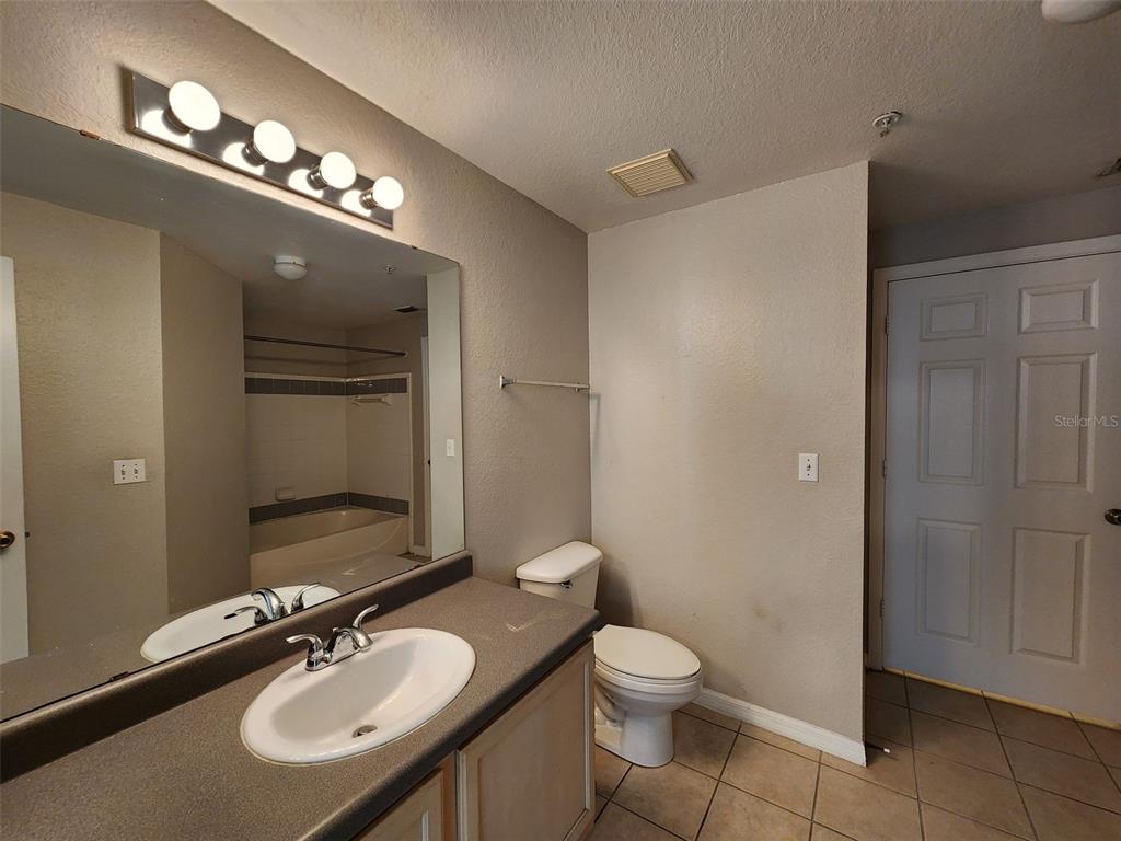 3250 Corona Village Way, Unit 101 Orlando, FL 32835 - Photo 18 of 31 a bathroom with a toilet a sink and mirror