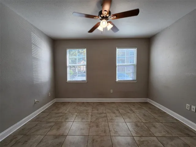 a view of an empty room with a ceiling fan and window