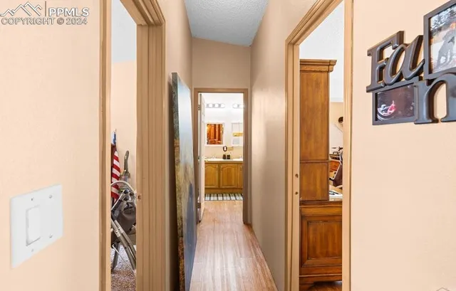 a view of a hallway with wooden floor and a bathroom
