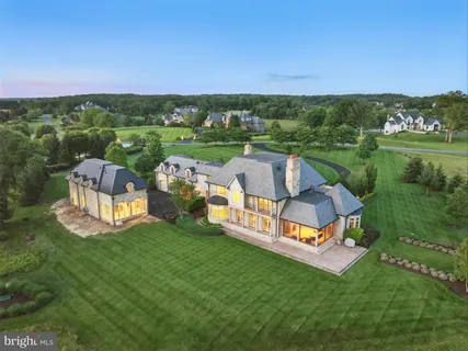 a view of a big house with a big yard and large trees