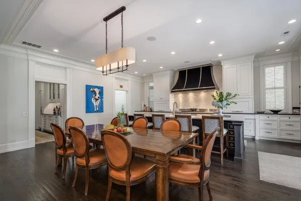 a kitchen with stainless steel appliances granite countertop a stove a sink dishwasher and a dining table with wooden cabinet