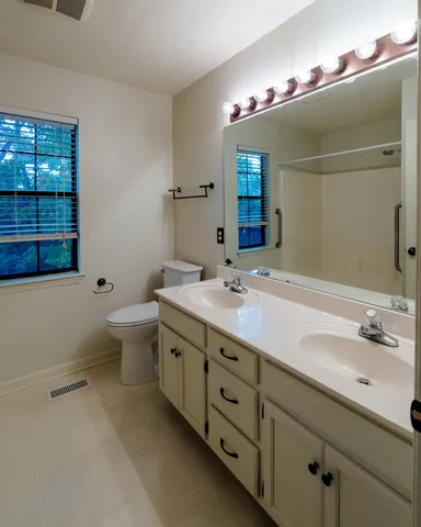 a bathroom with a double vanity sink a toilet and a mirror