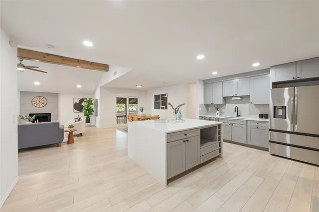 a large white kitchen with a stove a refrigerator a oven a dining table and chairs