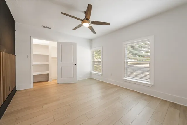 a view of an empty room with a window and wooden floor