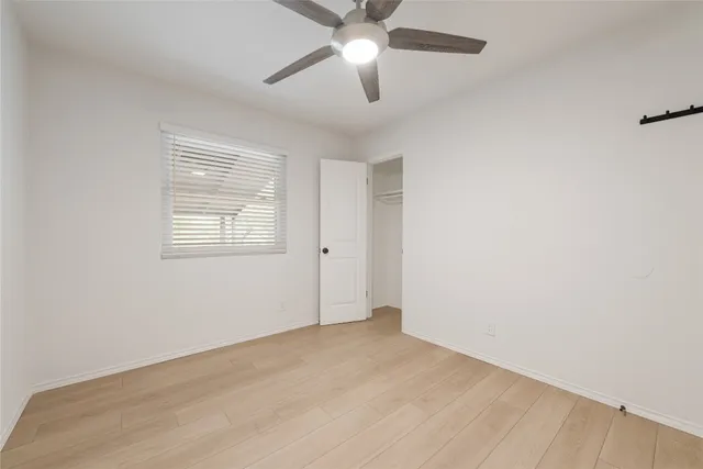 an empty room with a window and a ceiling fan