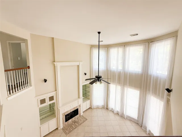 an empty room with wooden floor chandelier fan and windows