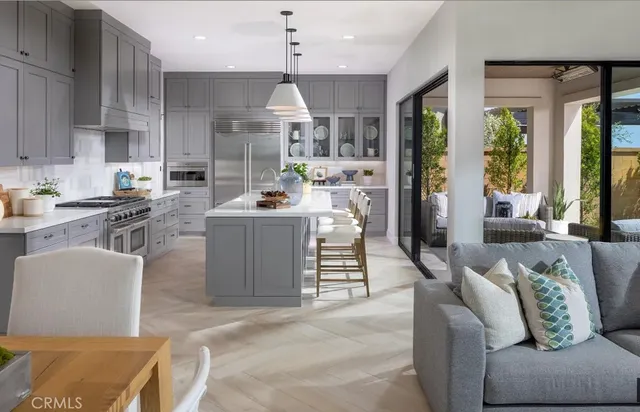 a living room with furniture a large window and stainless steel appliances