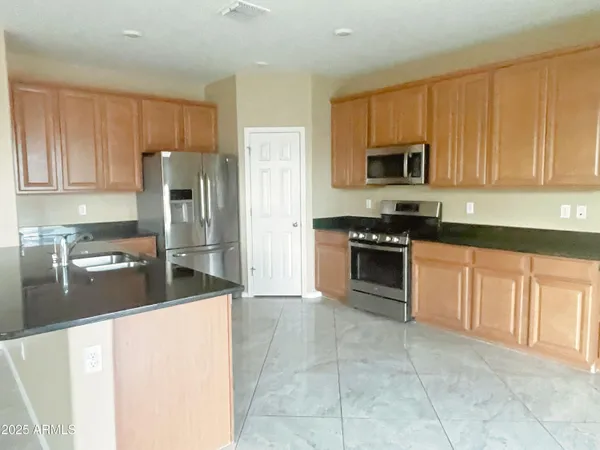 a kitchen with stainless steel appliances granite countertop a stove a sink and a refrigerator