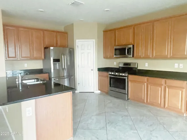 a kitchen with stainless steel appliances granite countertop a stove a sink and a refrigerator