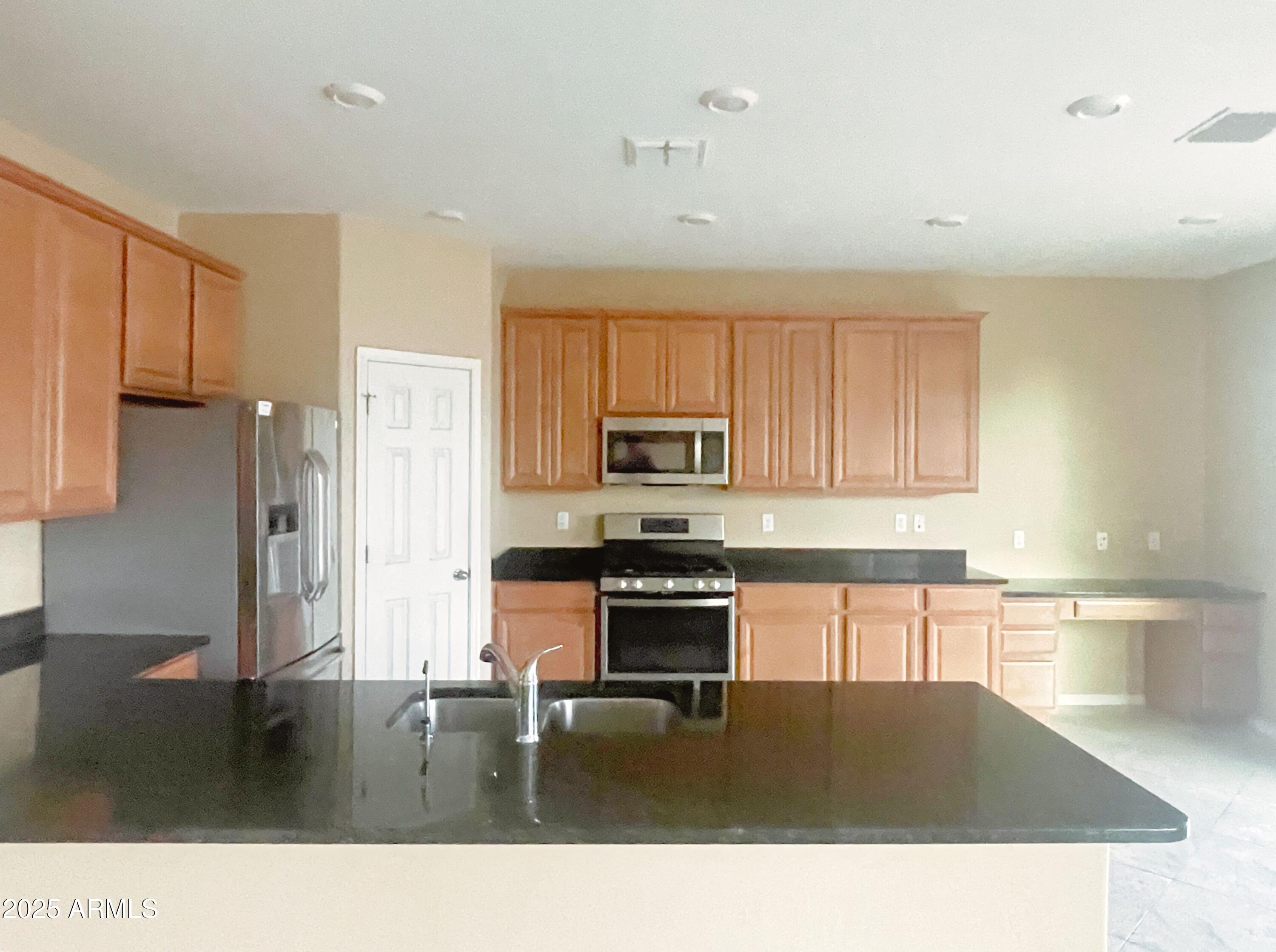 1121 East Regent Drive Gilbert, AZ 85298 - Photo 6 of 23 a kitchen with a stove a refrigerator and a sink with cabinets