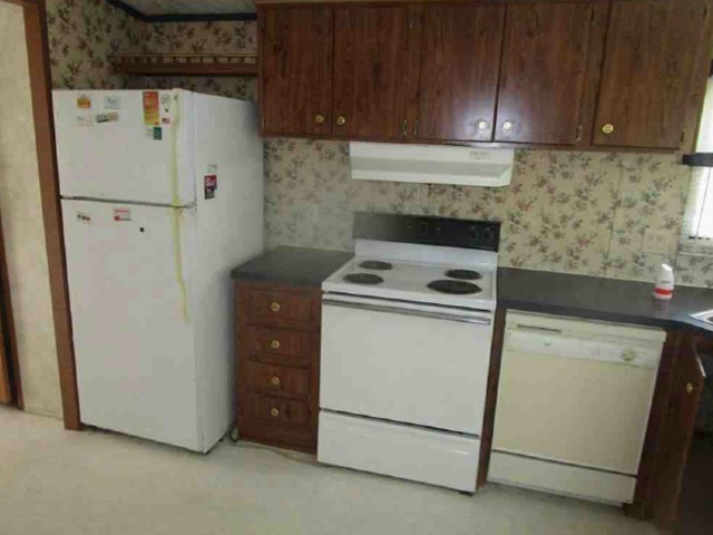 Rich wood cabinetry contrasts with the patterned wallpaper in this functional kitchen layout.