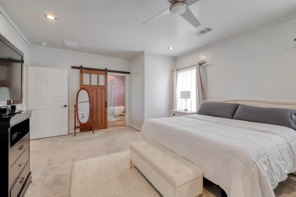 a spacious bedroom with a bed a mirror and a flat screen tv