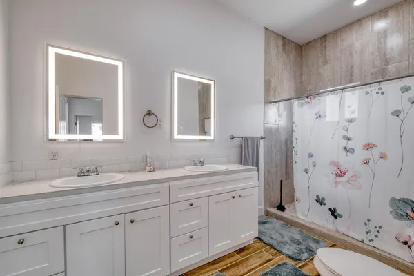 a spacious bathroom with double vanity sink a mirror a shower and a bathtub