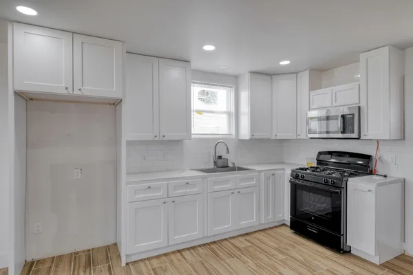 a kitchen with white cabinets and appliances