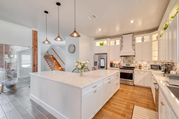 a large kitchen with stainless steel appliances kitchen island a large counter top a sink a stove and a refrigerator
