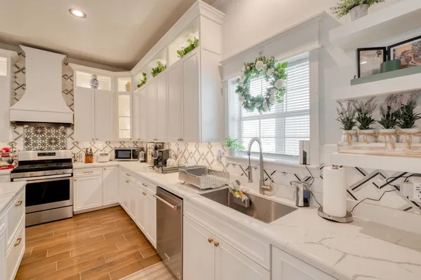a kitchen with stainless steel appliances a sink a stove and white cabinets next to a window