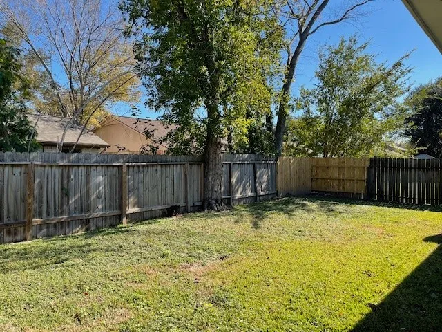 a view of backyard with wooden fence and trees