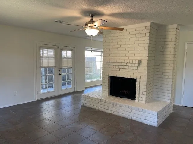 a view of an empty room with a fireplace and a window