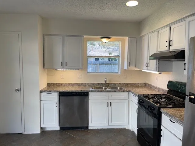 a kitchen with granite countertop a stove sink and cabinets