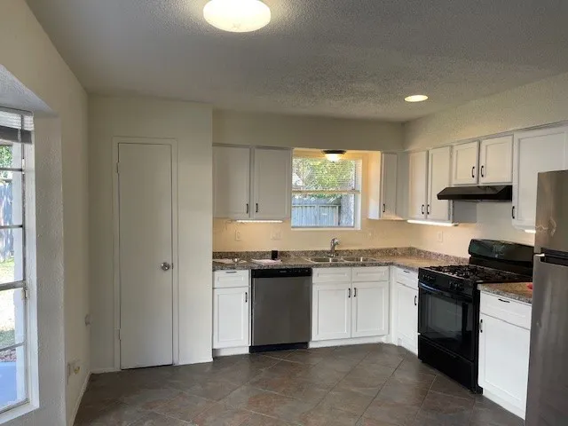 a kitchen with granite countertop stainless steel appliances a sink stove and cabinets