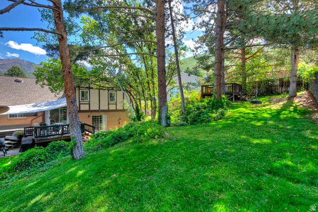 3310 Creek Road Salt Lake City, UT 84121 - Photo 4 of 49 Sloping grassy yard with mature trees and a mountain backdrop