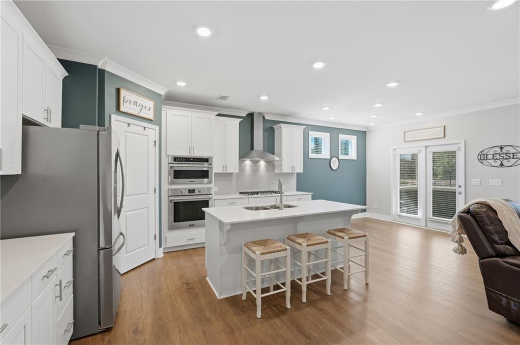 1413 Bluffs Ridge Way Canton, GA 30114 - Photo 12 of 62 a kitchen with stainless steel appliances kitchen island granite countertop a refrigerator a stove top oven a sink dishwasher and white cabinets with wooden floor