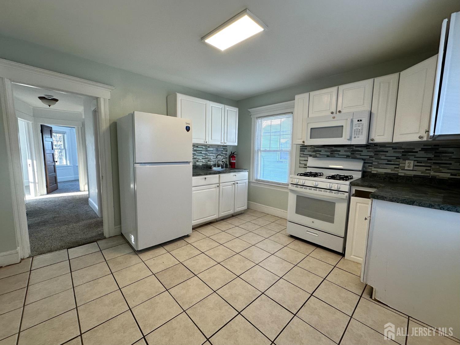 511 Grove Street Dunellen, NJ 08812 - Photo 8 of 9 a kitchen with a refrigerator a stove top oven and white cabinets