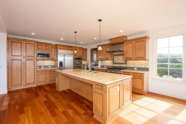 a kitchen with stainless steel appliances granite countertop a sink a stove and a refrigerator
