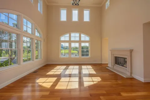 an empty room with windows and fireplace