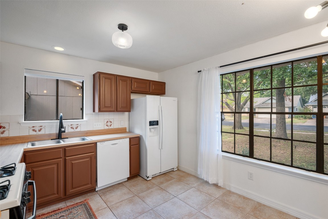 9833 Briar Ridge Drive Austin, TX 78748 - Photo 11 of 29 a large white kitchen with a sink large window and stainless steel appliances