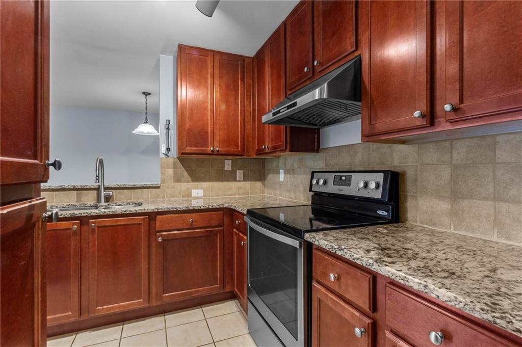 3650 Ashford Dunwoody Road Northeast, Unit 227 Atlanta, GA 30319 - Photo 13 of 23 a kitchen with granite countertop stainless steel appliances wooden cabinets and a sink