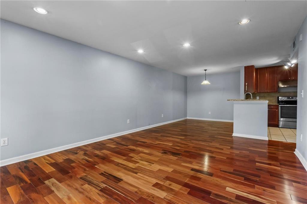 3650 Ashford Dunwoody Road Northeast, Unit 227 Atlanta, GA 30319 - Photo 5 of 23 a view of empty room with wooden floor and kitchen view
