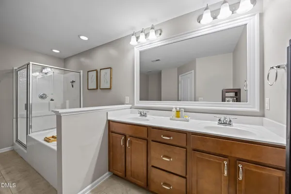a bathroom with a tub a sink double vanity and mirror