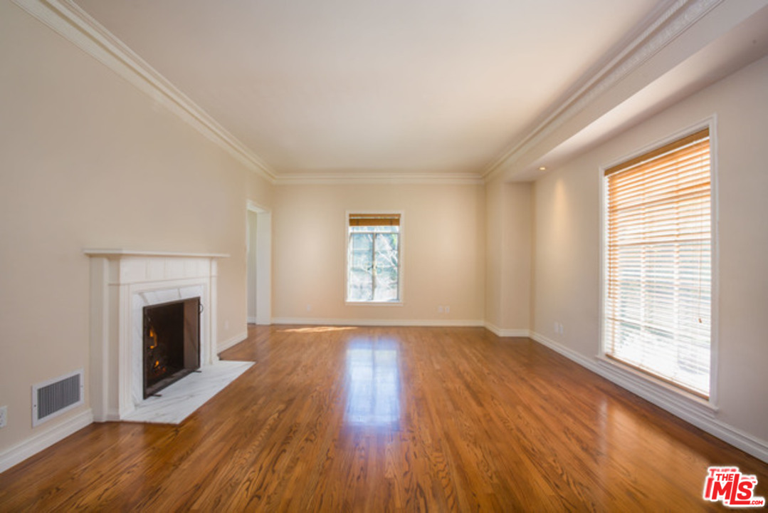 171 South Rodeo Drive Beverly Hills, CA 90212 - Photo 2 of 21 an empty room with wooden floor fireplace and windows