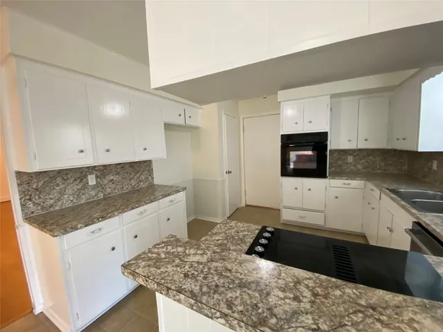 a kitchen with granite countertop white cabinets and stainless steel appliances
