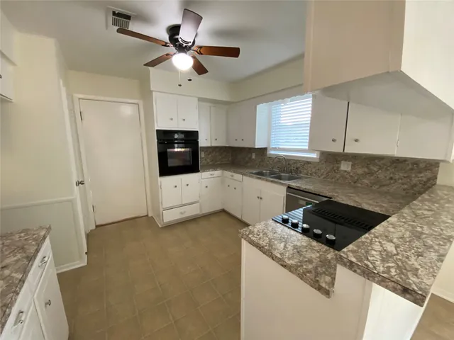 a kitchen with granite countertop a sink a stove a microwave and cabinets