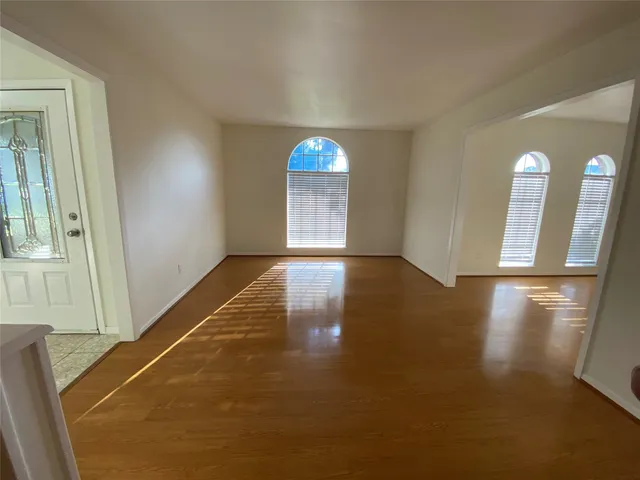 a view of a livingroom with wooden floor and a kitchen
