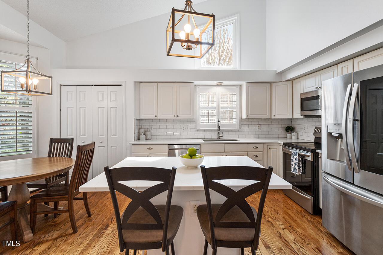 2320 Kendricks Court Raleigh, NC 27613 - Photo 11 of 35 a kitchen with stainless steel appliances granite countertop a dining table chairs refrigerator and cabinets