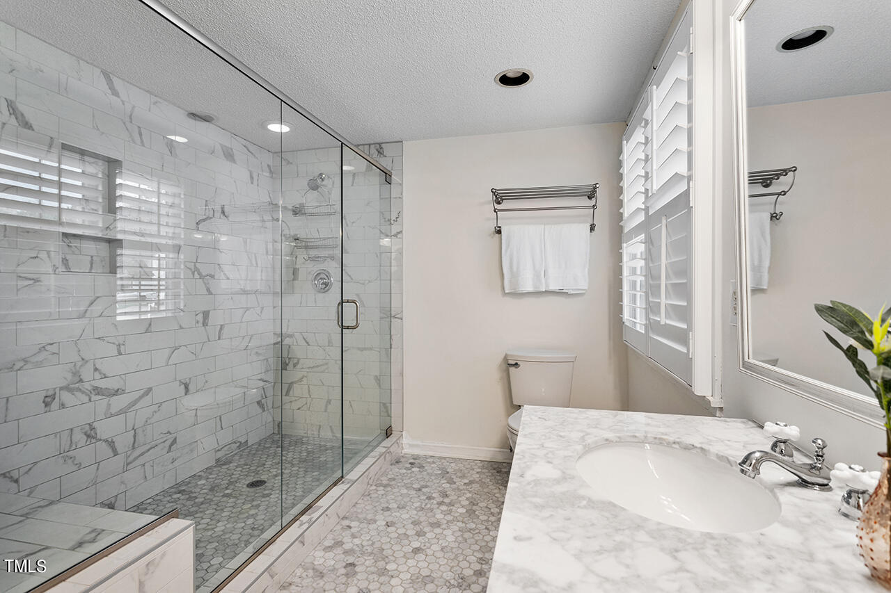 2320 Kendricks Court Raleigh, NC 27613 - Photo 23 of 35 a bathroom with a granite countertop sink a shower and a mirror