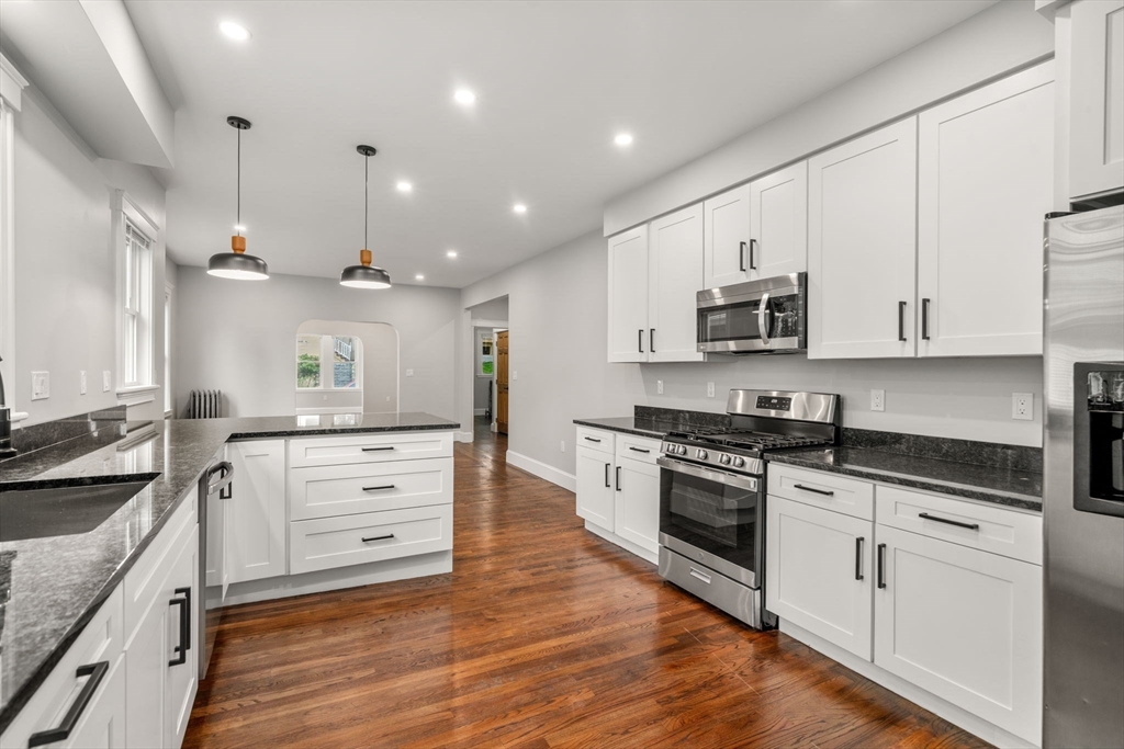 21-23 Westmore Road Boston, MA 02126 - Photo 11 of 42 a large kitchen with granite countertop a stove top oven a sink a counter space and cabinets