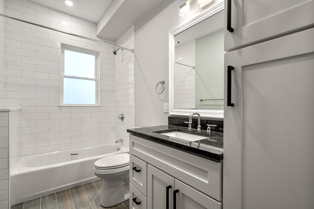 21-23 Westmore Road Boston, MA 02126 - Photo 37 of 42 a bathroom with a granite countertop sink toilet a mirror and bathtub