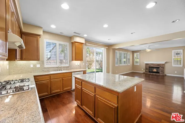 a large kitchen with stainless steel appliances granite countertop a sink and dishwasher with wooden cabinets