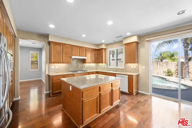 a kitchen with a stove a refrigerator a sink dishwasher with wooden cabinets and wooden floor