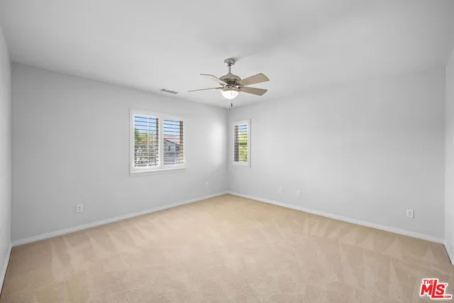 an empty room with windows and chandelier fan
