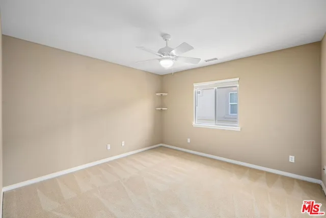 an empty room with a window and a fan